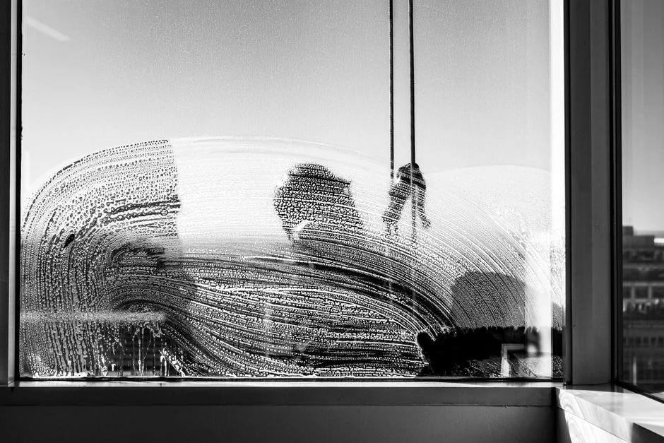 project-02-b Tall glass building facade with a suspended platform used for window cleaning.